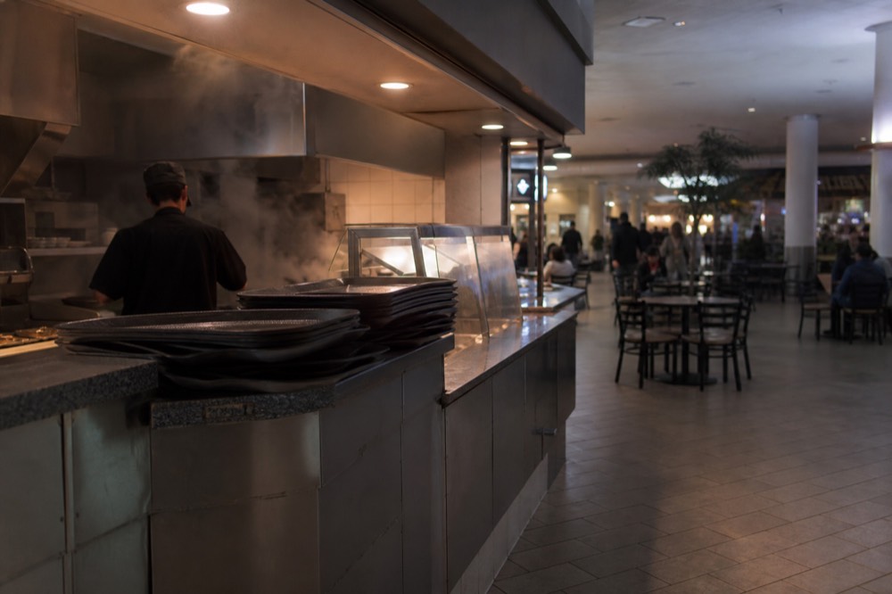Food court counters and seating in a mall basement, no text, no logos, no people.